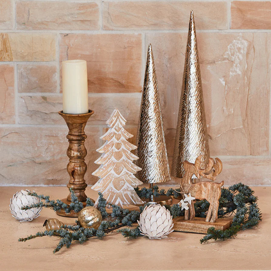 Decorative setup with Christmas trees, candles, and ornaments against a brick wall.