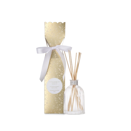 A reed diffuser set featuring a clear glass bottle with natural reeds and a tall, textured gold gift box tied with a white ribbon.